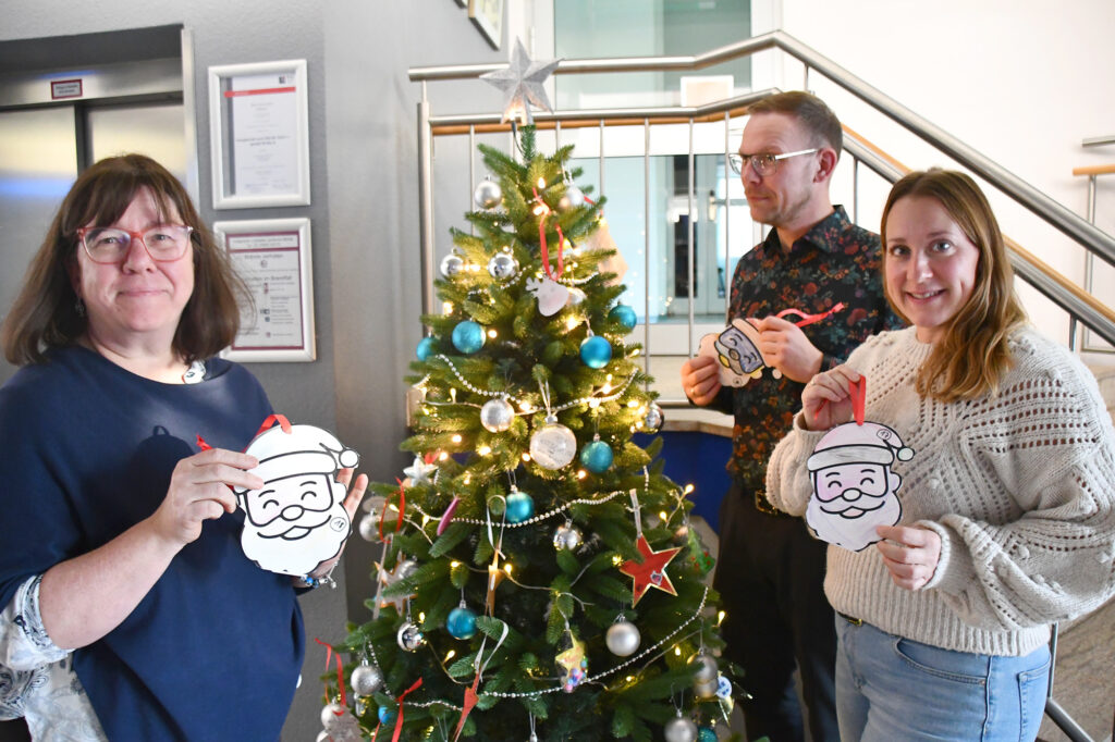 Mitarbeiterinnen und Mitarbeiter der Wolmirstedter Stadtverwaltung pflücken erste Weihnachtswünsche vom Wunschbaum.