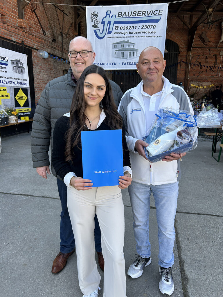 Wolmirstedts Bürgermeister Mike Steffens beglückwünscht Holger Kudernatsch und seine Tochter Michelle zum Firmenjubiläum